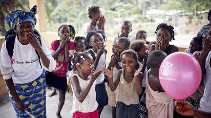 Glada barn skrattar tillsammans med personal från rädda barnen