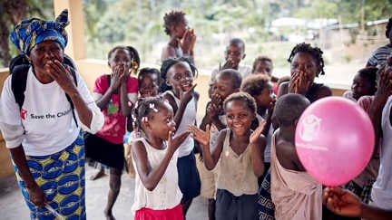 Glada barn skrattar tillsammans med personal från rädda barnen