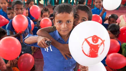 Glada barn med ballonger som det står rädda barnen på