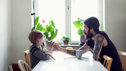 En pappa och ett barn sitter vid köksbordet. 