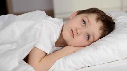En pojke som ligger nedbäddad i sängen. 