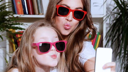 Två flickor med solglasögon tar en selfie.