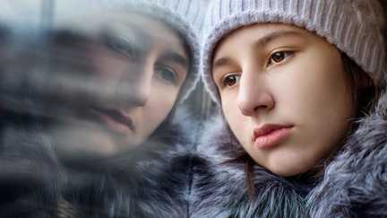 En flicka som blickar ut genom ett fönster.