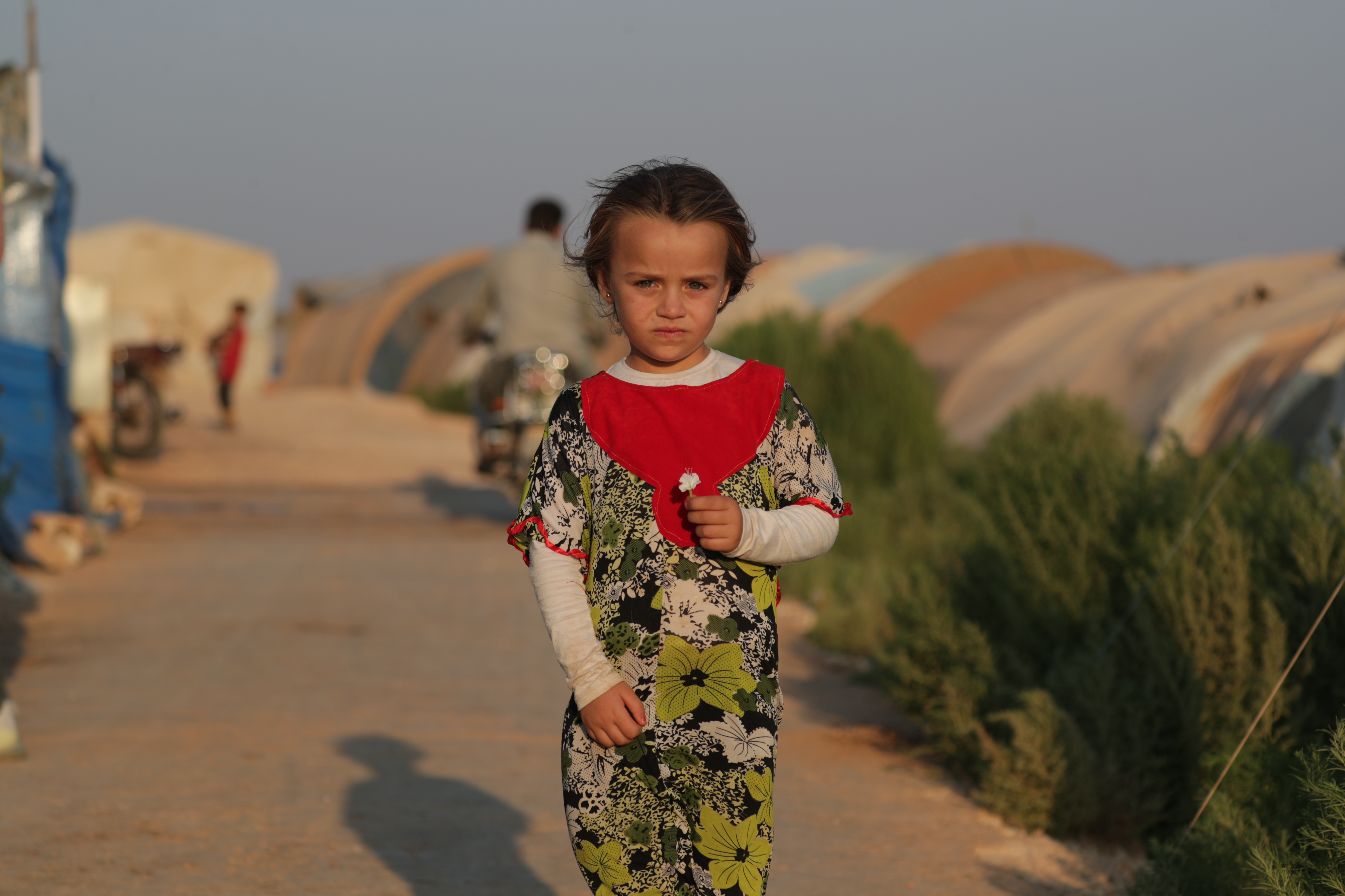 Abeer*, 6, står utanför sin familjs tält i det syriska flyktinglägret där de bor.
