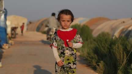 Abeer*, 6, står utanför sin familjs tält i det syriska flyktinglägret där de bor.